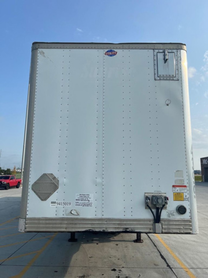 Box truck trailer rear showing DOT placards and hitch area with wiring and reflectors.