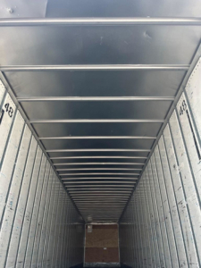 Interior of a metal trailer with ribbed walls and ceiling, numbers 485 and 488 visible on the side rails, landing at the far end.