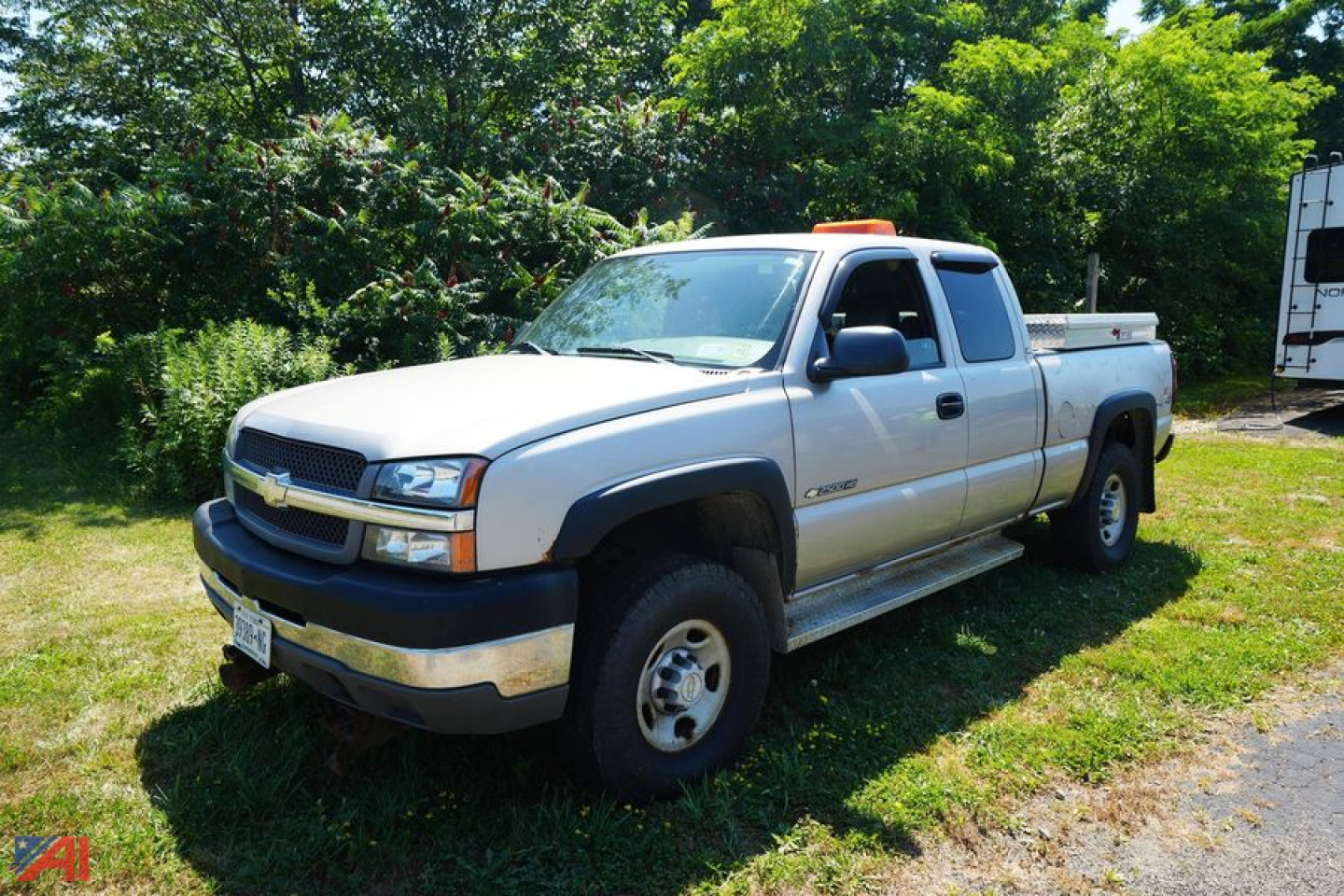 Chevrolet Silverado 2500HD pickup truck in a driveway, light gray color, extended cab, two-tone bumper, orange clearance lights on cab roof.