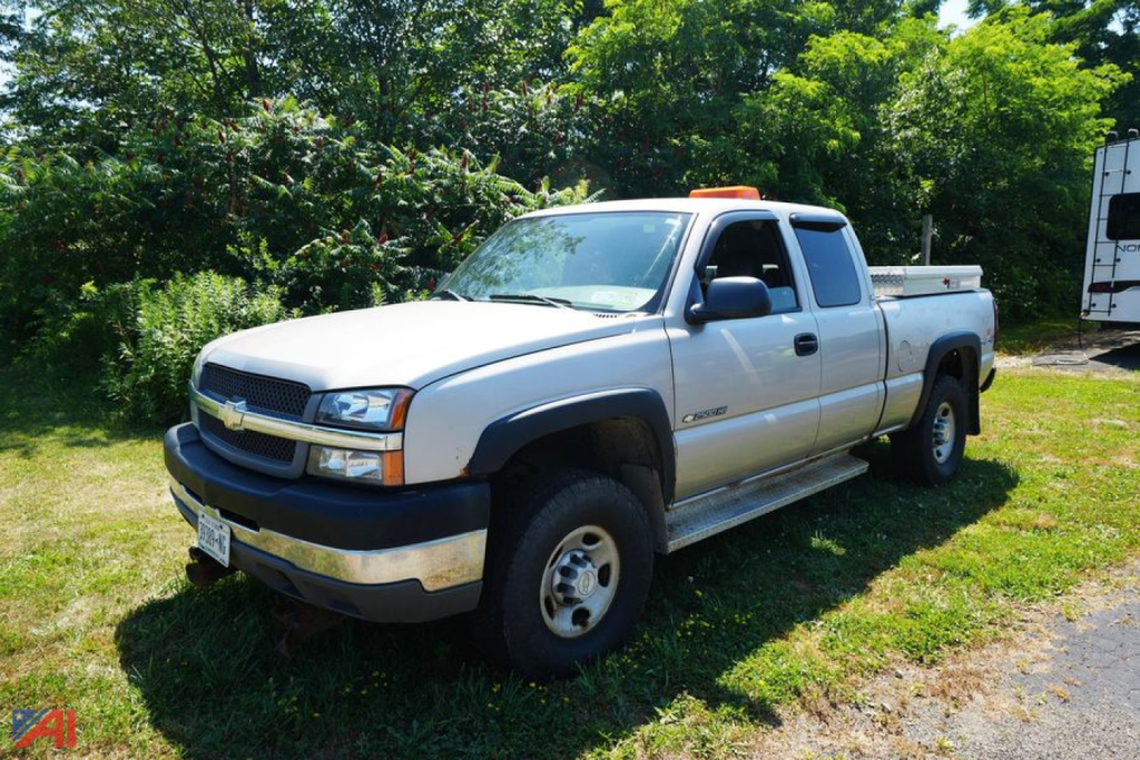Chevrolet Silverado 2500HD pickup truck in a driveway, light gray color, extended cab, two-tone bumper, orange clearance lights on cab roof.