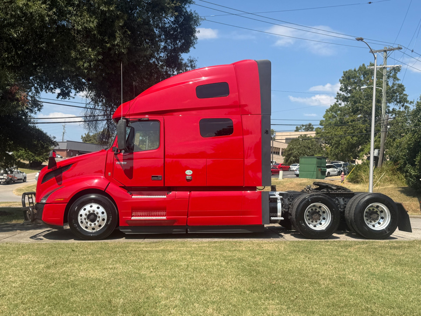 Volvo VNL64T760 sleeper tractor in red, side profile view showing cab with sleeper, long hood, dual rear axles, and exposed fuel tanks.