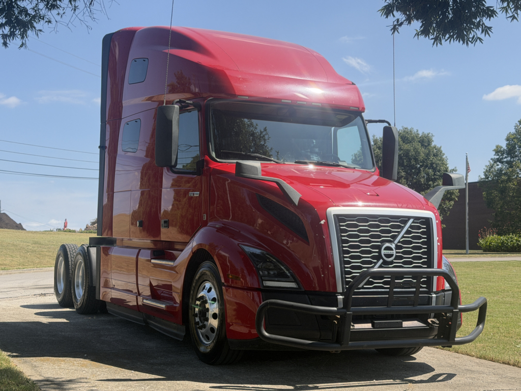 Volvo VNL64T760 truck in red, front/side view showing large chrome grille, bull bar, sleeper cab, and dual rear axles.