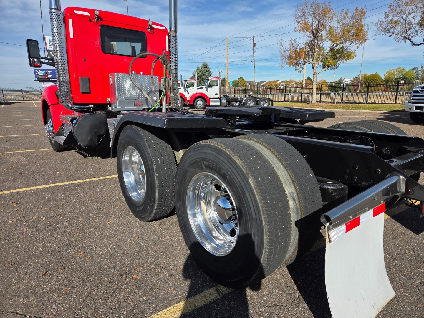 Kenworth T880 2020 Conventional Daycab chassis with dual rear axles and chrome wheels, red cab, fuel tanks, fifth wheel area visible.