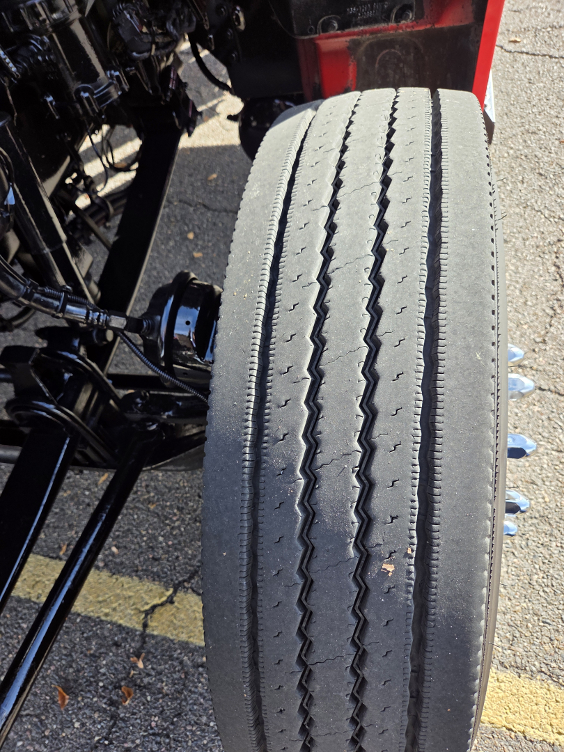 Kenworth truck wheel and front suspension visible with tire tread pattern in view