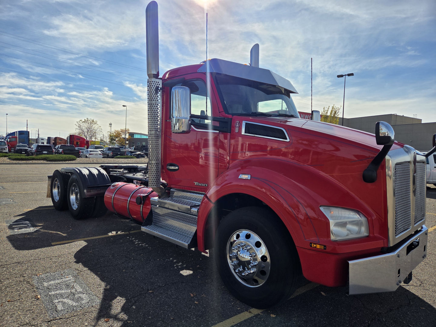 Kenworth T880 conventional day cab truck in red, side view showing cab, exhaust stacks, fuel tanks, and chrome wheels.