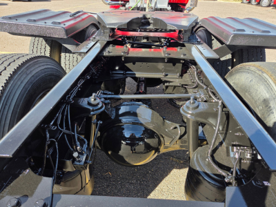Kenworth T880 chassis rear view showing drive axle housing, leaf spring suspension, frame rails, dual fuel/wuel tanks and various hoses.
