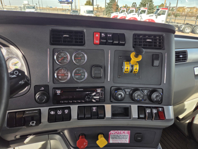 Dashboard of a 2020 Kenworth T880 showing multiple gauges, ignition switches, yellow safety lever, and control dials in driver cockpit.