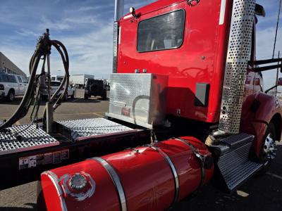 Fuel tank and side view of a red Kenworth T880 cab with chrome air intake, metal steps, and storage box.