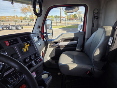 Interior of a Kenworth T880 cab showing steering wheel, dashboard with controls, driver seat, passenger seat, and door panel.