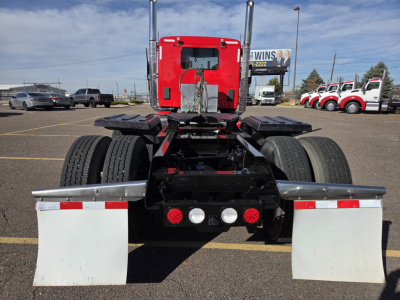 Truck rear view of a 2020 Kenworth T880 conventional daycab showing dual rear axles, chassis, fifth wheel, and mud flaps with stock number plate in background.