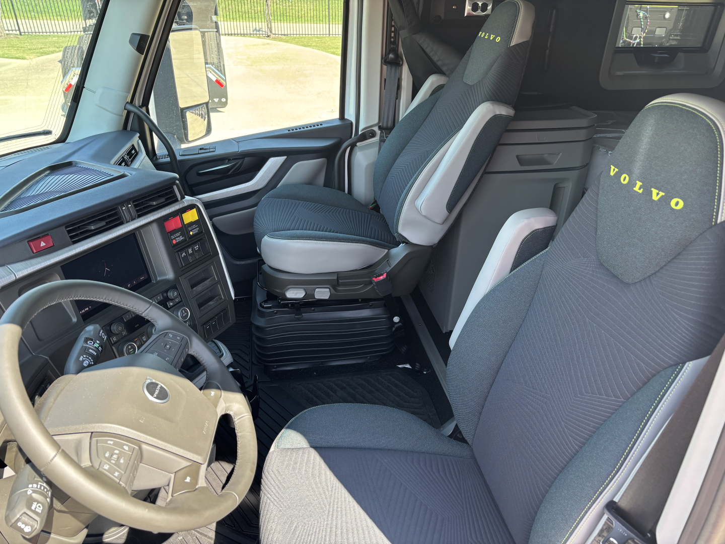 Volvo VNL cabin interior showing driver seat and passenger seat with Volvo branding, steering wheel, dashboard, and center console.