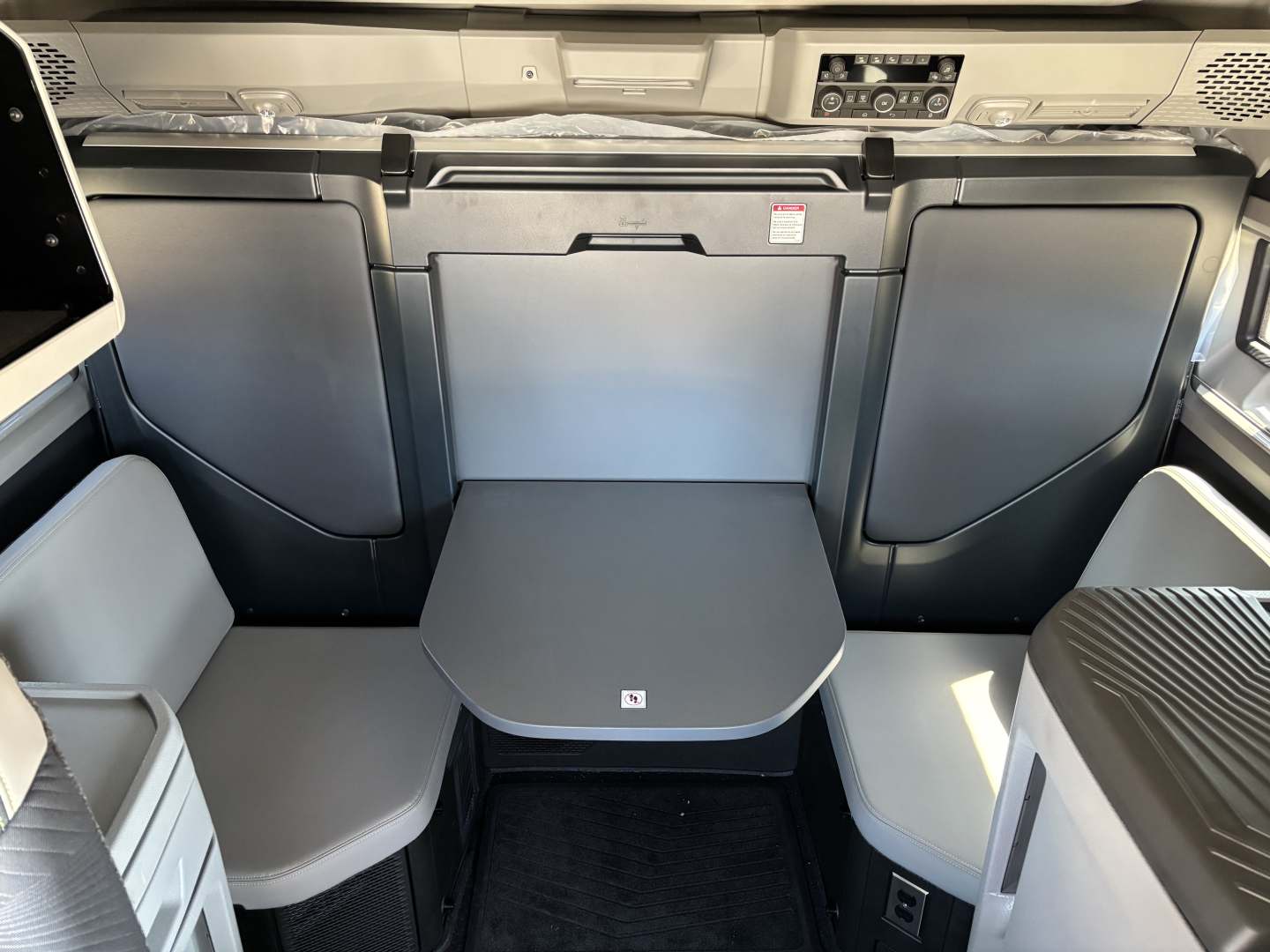 Volvo VNL64T860 cabin interior showing front seating with fold-out table, center console, and surrounding storage panels.