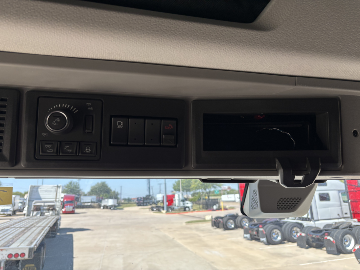 Volvo VNL64T860 dash area with control panel and empty cubby, front windshield view showing dealer lot.