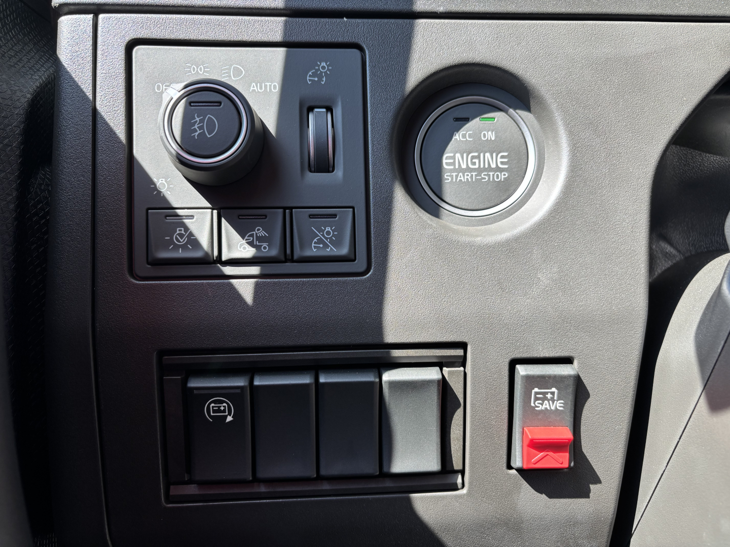 Volvo VNL64T860 cab interior showing engine start-stop button and control panel with switches and 12V/auxiliary buttons.