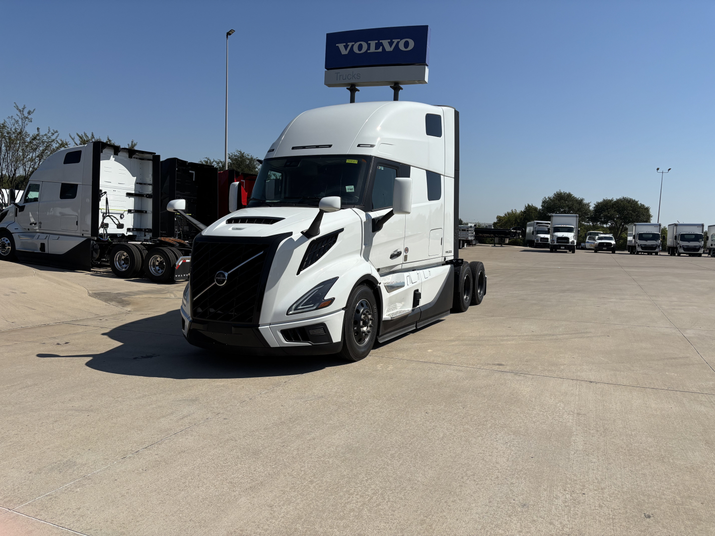 Volvo VNL64T860 tractor in dealership lot with other trucks visible in background; front grille and headlights clearly shown.