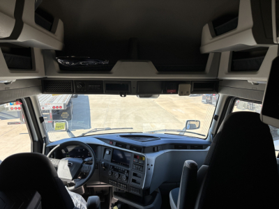 Front interior of a Volvo VNL64T860 truck cab showing dashboard, steering wheel, and overhead storage compartments.