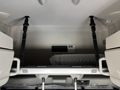 Volvo VNL64T860 sleeper cab interior showing sleeper berth with two black shoulder harnesses and storage compartments