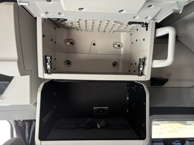 Volvo VNL64T860 cab interior showing open overhead storage compartment and lower storage bay with wiring and mounting brackets.