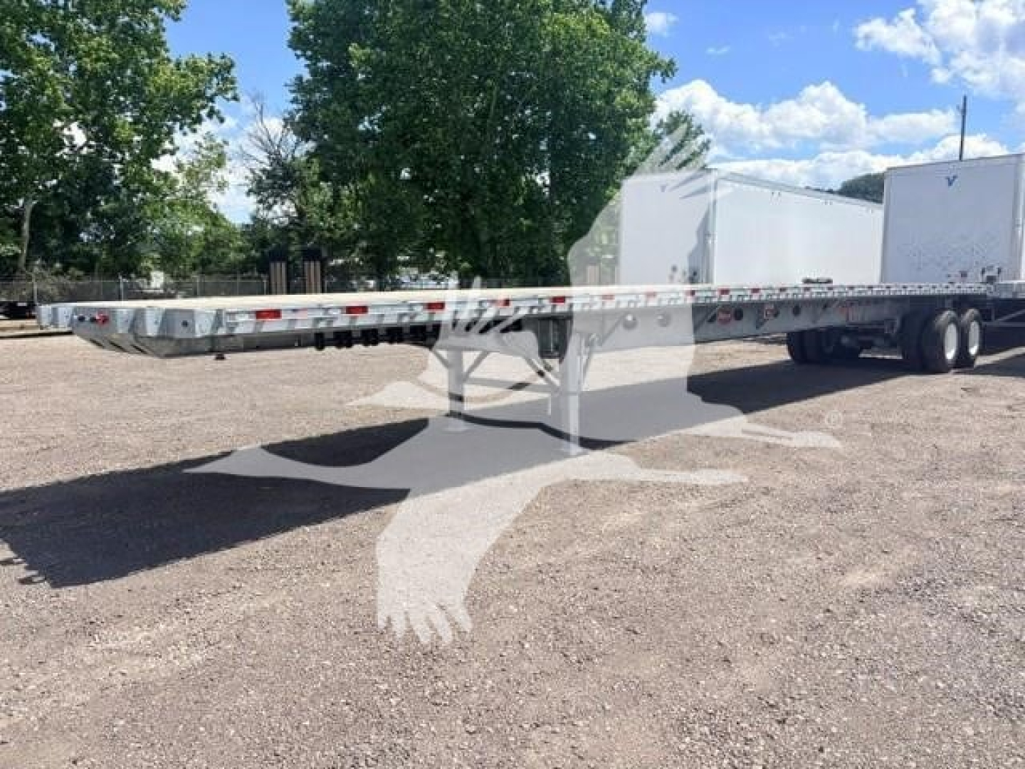 Flatbed trailer long chassis with gooseneck, dual rear axles, aluminum deck, wheel wells, and reflective tape along sides.