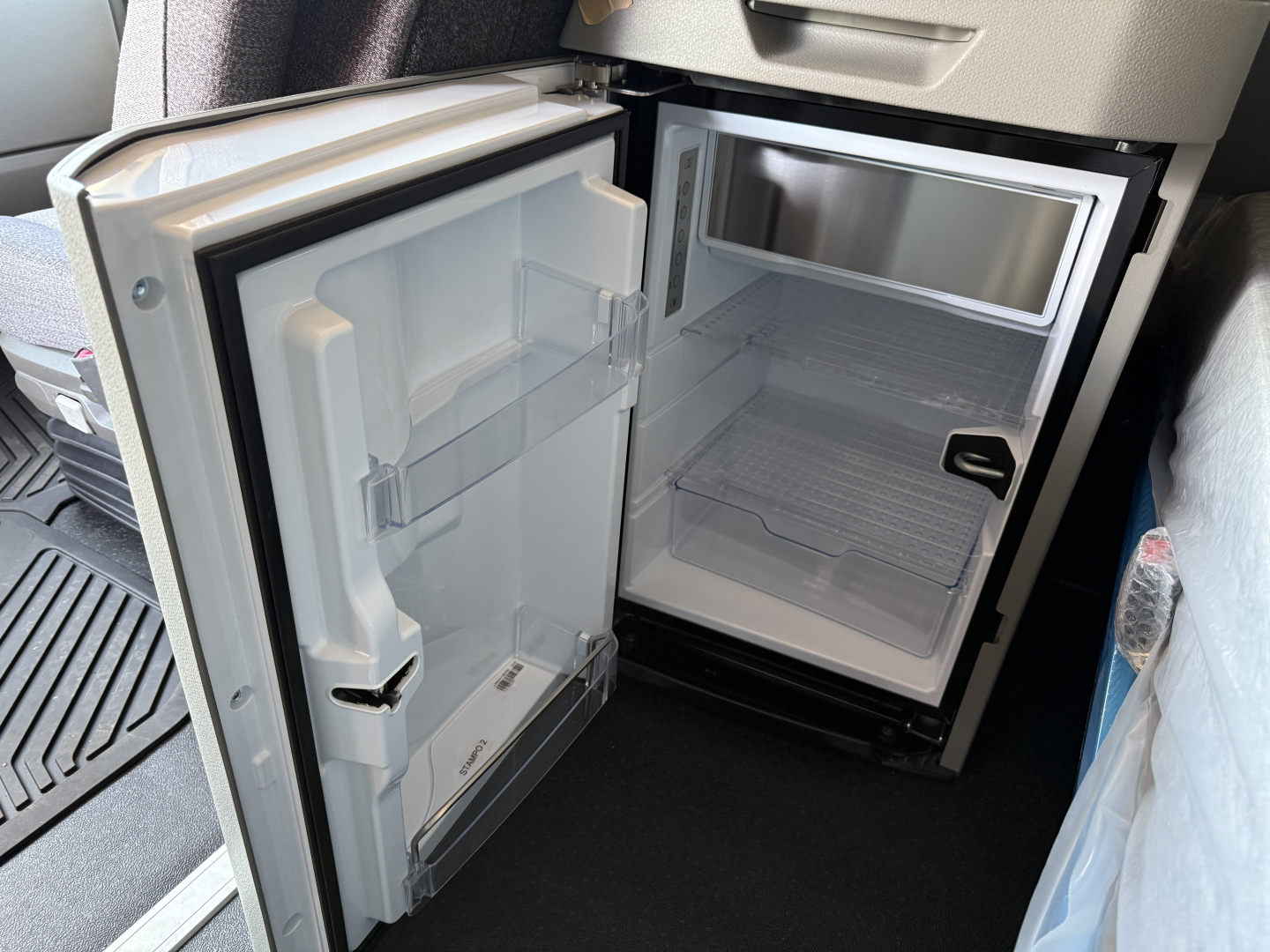 Mini fridge/freezer section in Volvo VNL64T840 truck cab showing open doors and empty shelves.
