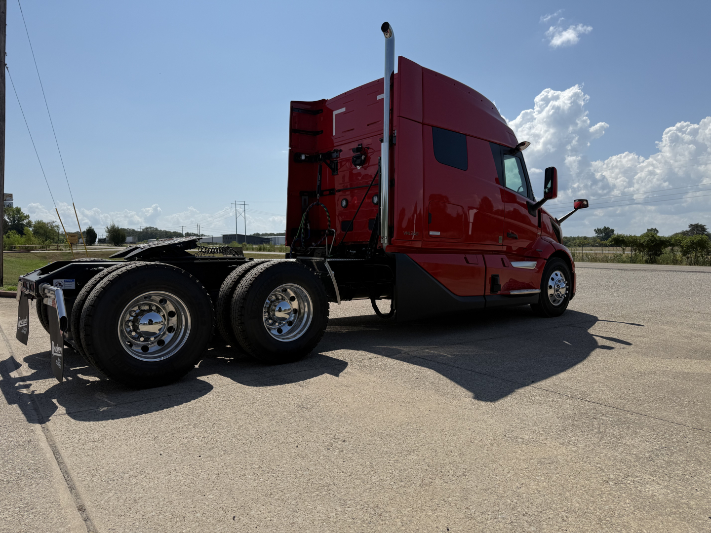 Volvo VNL64T840 tractor from rear-left side view showing red cab and dual rear axles, chrome wheels, and sleeper cab profile.