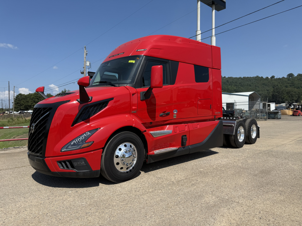 Truck side view of a red Volvo VNL64T840 with sleeper cab, front grille, and chrome wheels. No visible text other than reflections.