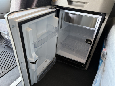 Mini fridge/freezer section in Volvo VNL64T840 truck cab showing open doors and empty shelves.