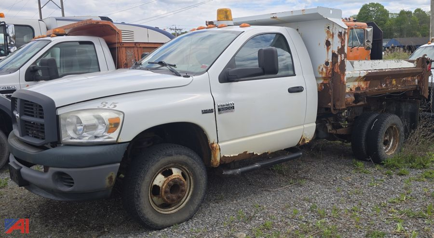 Dodge Ram 3500 heavy duty dump truck in-service showing white cab and Rusted dump bed with visible rust patches and dual rear wheels.