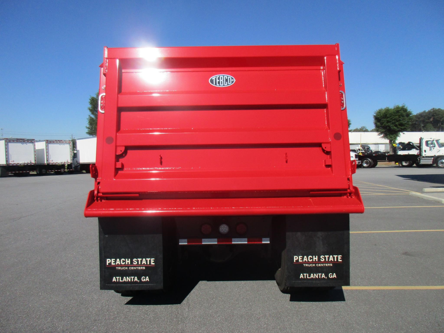 Rear view of a red dump truck bed with black mud flaps showing Peach State Atlanta GA branding.
