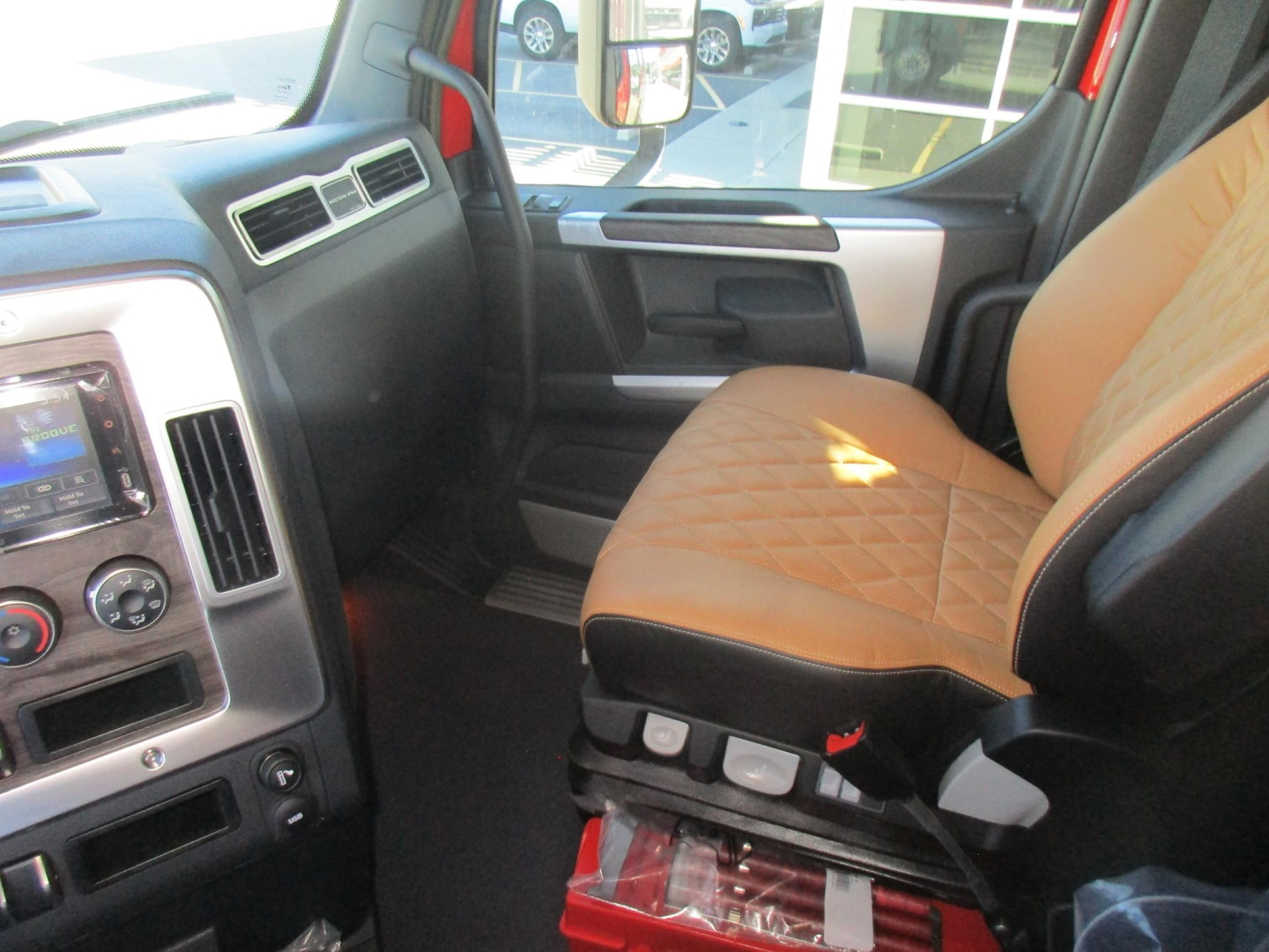 Cab interior of a new Western Star 47X dump truck showing tan diamond-stitched driver seat, center console controls, and dashboard with touchscreen.