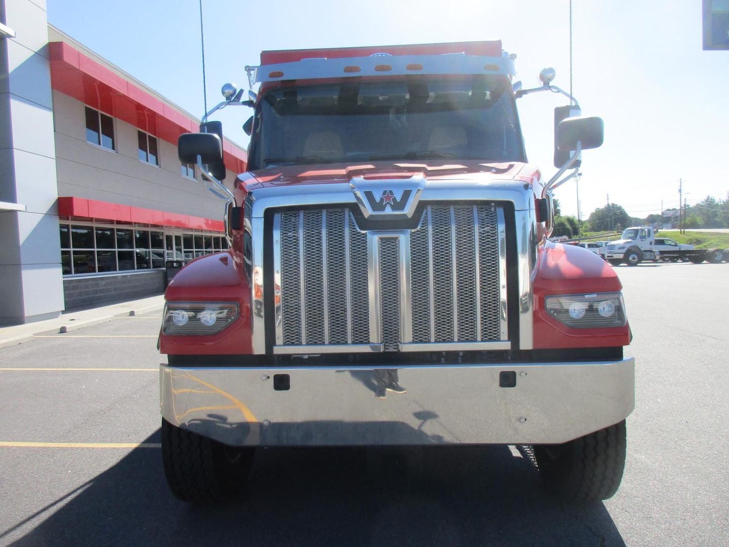 Front view of a red Western Star 47X dump truck with chrome grille, large bumper, and side mirrors visible.