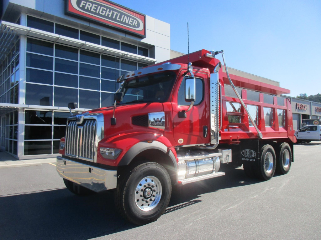 Western Star 47X dump truck with red cab and dump body parked outside dealership