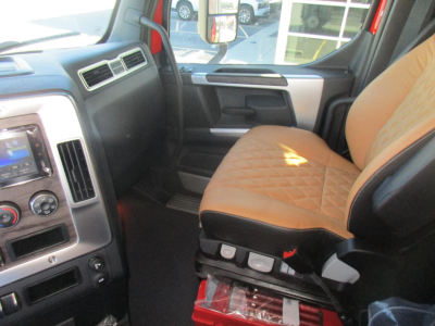 Cab interior of a new Western Star 47X dump truck showing tan diamond-stitched driver seat, center console controls, and dashboard with touchscreen.