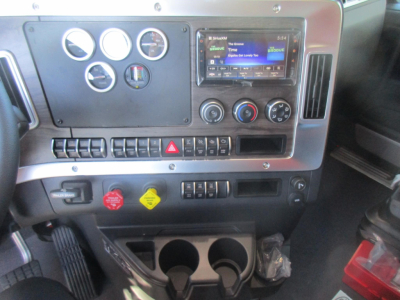 Dashboard of a 2027 Western Star 47X dump truck showing gauges, multimedia display, climate controls, hazard switch, and credential quick-access buttons.