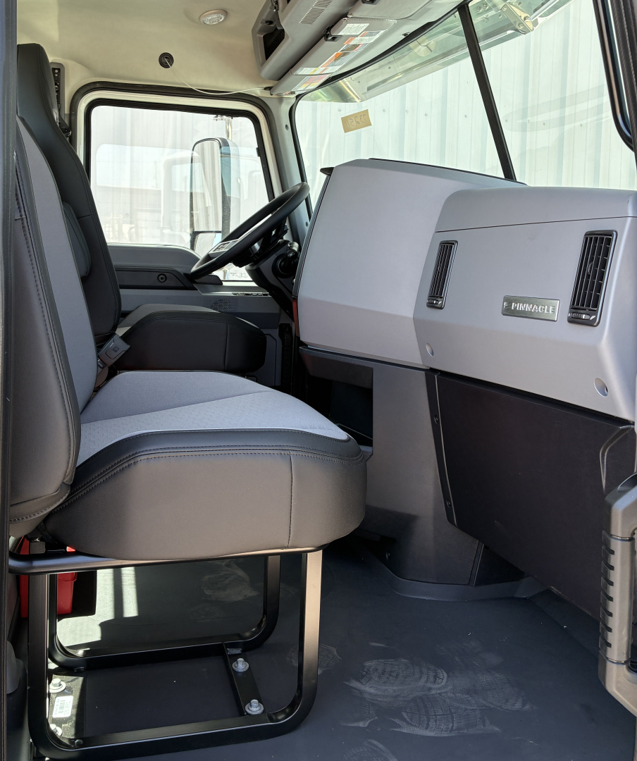 Truck cab interior of a 2027 Mack PI64T showing driver seat, dashboard, and steering wheel with gray and black color scheme.
