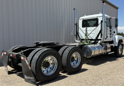 2027 Mack PI64T conventional daycab truck side and rear view showing dual rear axles, chrome fuel tanks, white cab, and fifth wheel with Wheeled rear mud flaps.