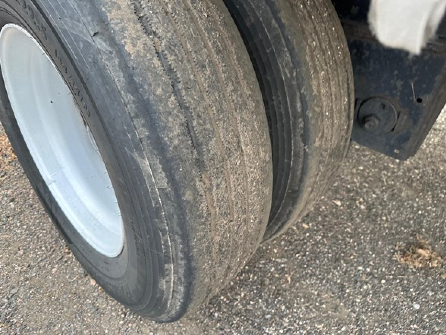 Dual rear trailer wheels with dirt on tires and white rims, part of a utility spread air combo flatbed trailer.
