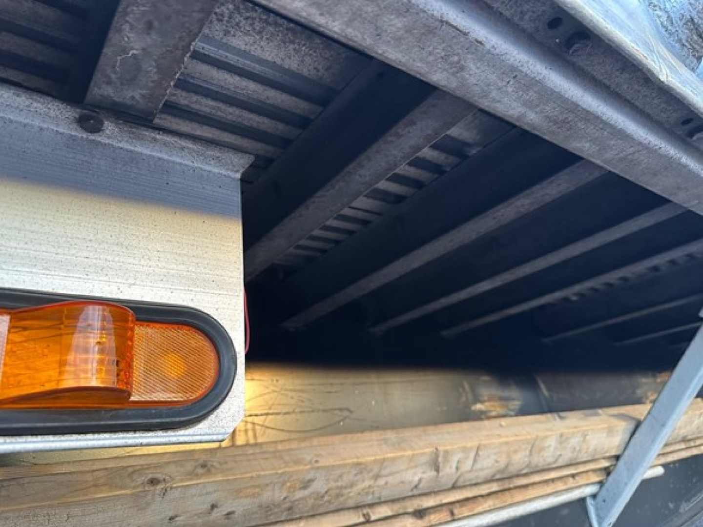 Trailer rear with amber side marker light and wooden deck edge in view; utility spread air combo flatbed truck trailer components visible.