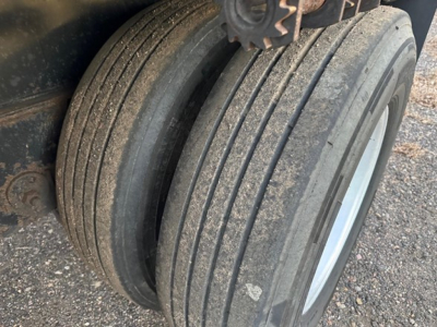 Tri-axle trailer tire close-up showing dual tires and wheel well in in-service condition.