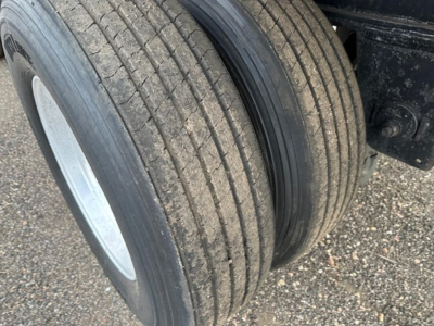 Trailer dual wheels with tires and rims; flatbed utility trailer undercarriage visible.