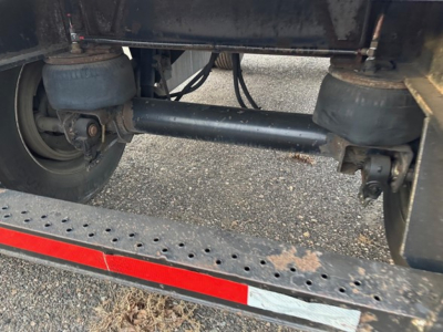Trailer undercarriage showing dual suspension air bag/leaf spring components and crossbar undercarriage with step perforated steel.