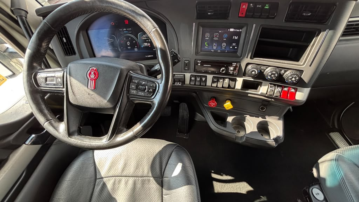 Kenworth T680 cab interior showing steering wheel and dashboard with controls and touchscreen display.