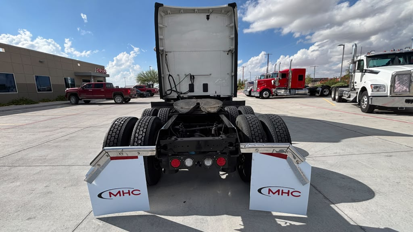 Rear view of a 2024 Kenworth T680 tractor showing spare mud flaps with MHC logos and rear fenders.