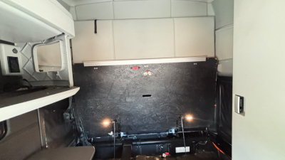 Kenworth T680 sleeper cab interior cargo area with side storage and rear wall panels, view from side near cab.