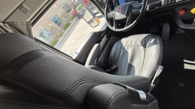 Kenworth T680 interior cab view showing steering wheel, driver seat, and dashboard area.