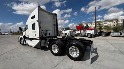 Kenworth T680 truck chassis view with sleeper cab and rear dual-axle configuration, white exterior, parking lot background.