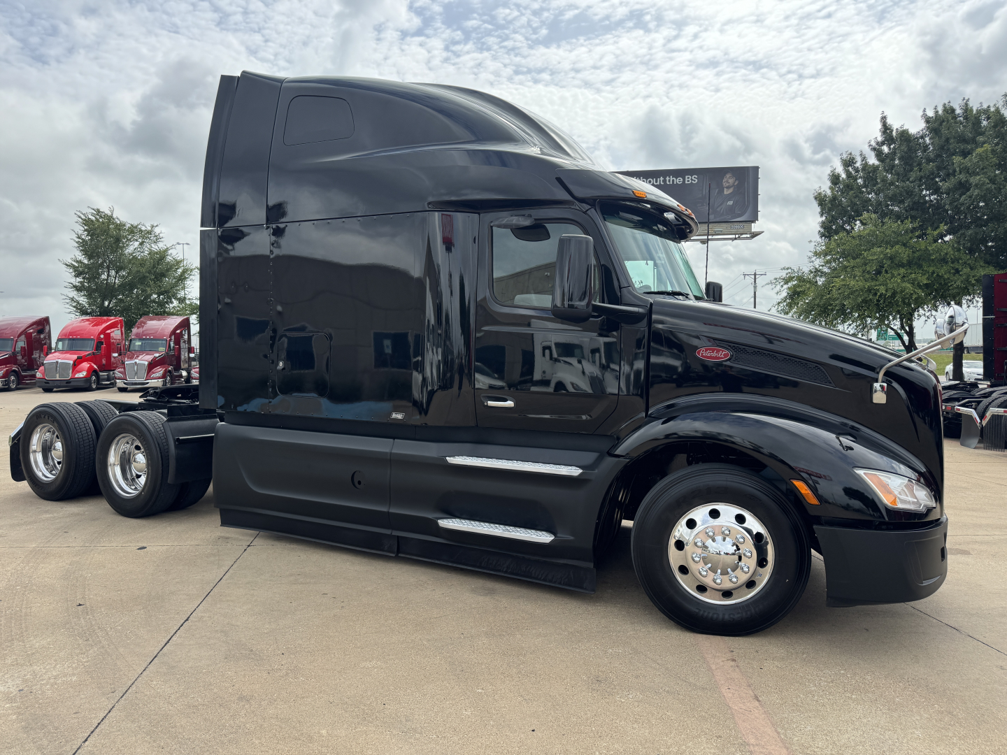 Peterbilt 579 conventional sleeper tractor in black, side view, showing cab, front wheel, chrome hubcap, and sleeper height.