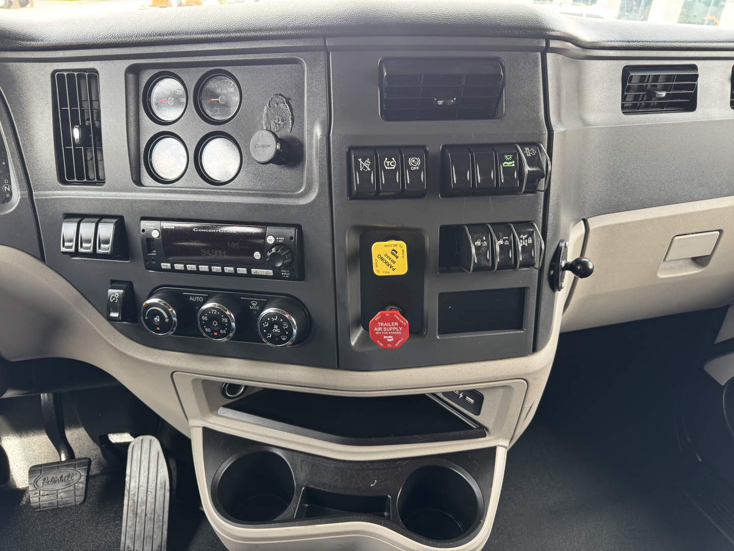 Peterbilt 579 dash and center console showing gauges, switches, and cup holders in a used truck interior.