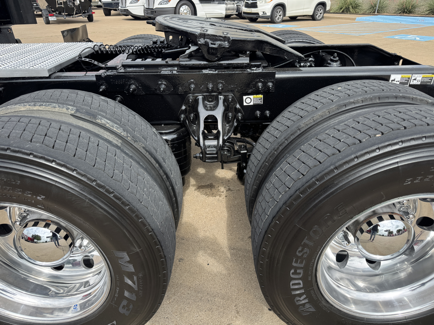 Dual rear tractor tires and fifth wheel hitch area of a Peterbilt 579 tractor showing dual wheels with Bridgestone tires and chrome hubcaps, undercarriage frame and προσ