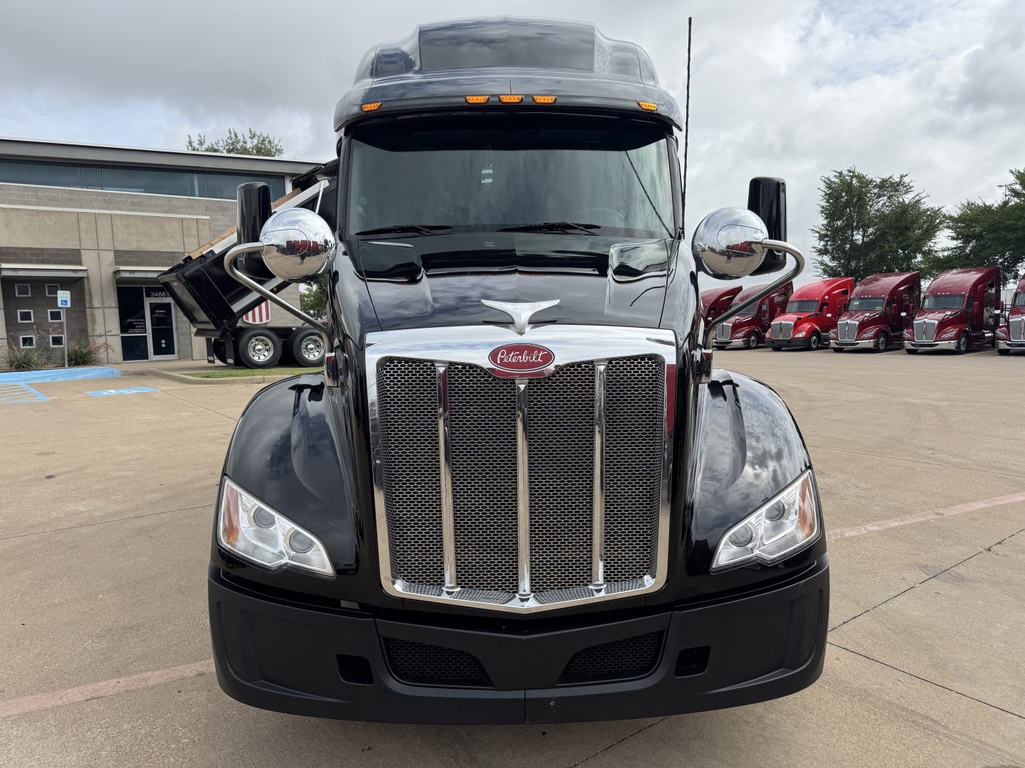 Peterbilt 579 truck front view showing chrome grille, large headlights, and side mirrors in a parking lot.
